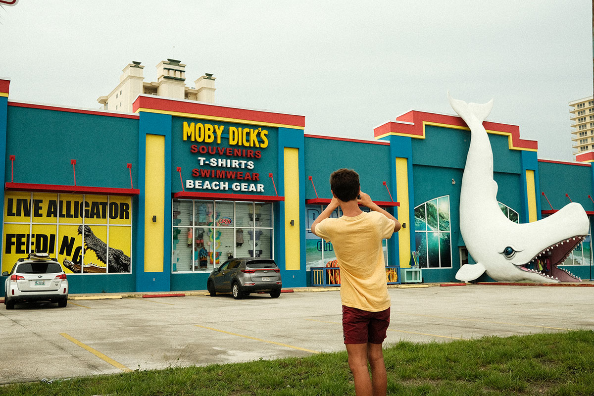 boy taking picture of Moby Dick's souvenir shop sign
