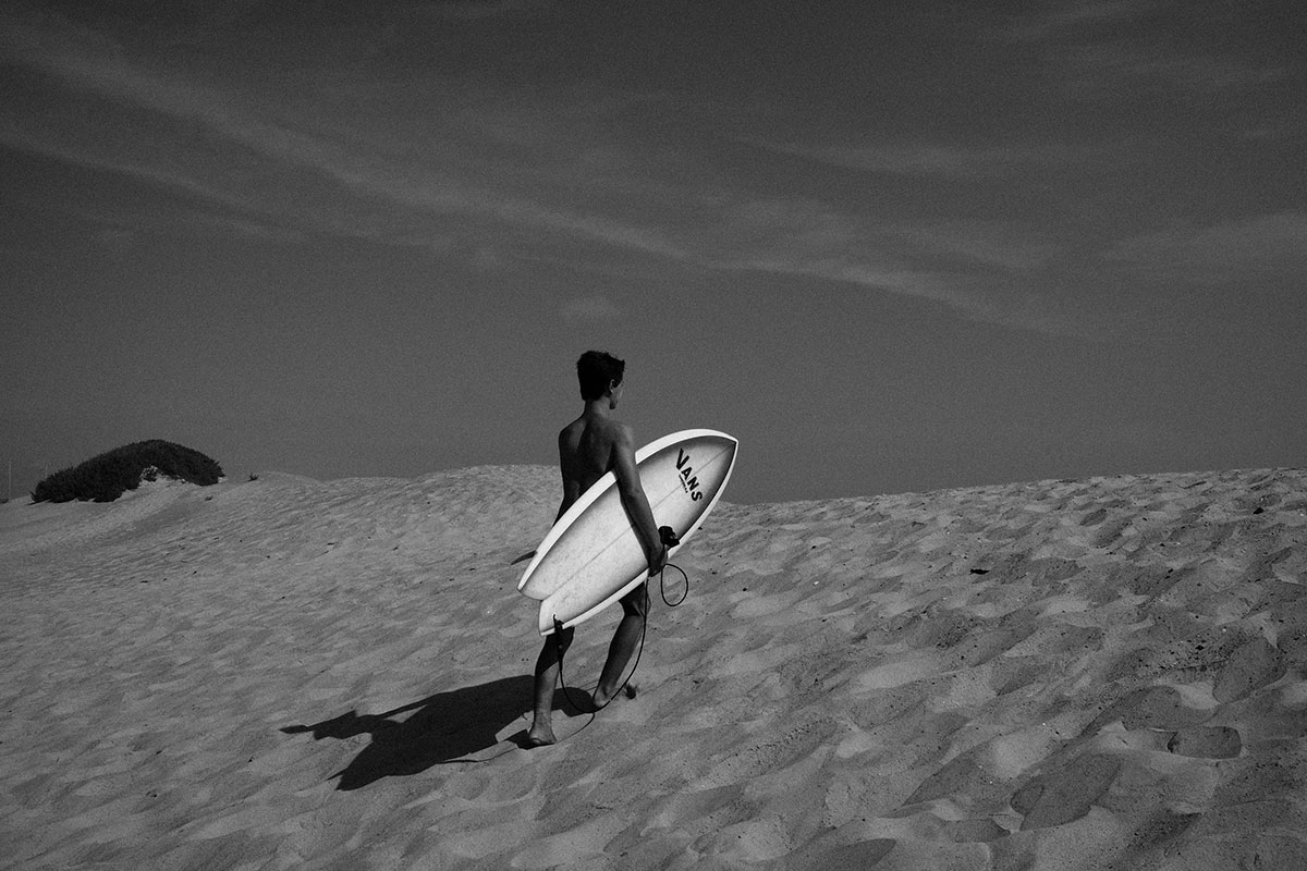 surfer walking over sand dune