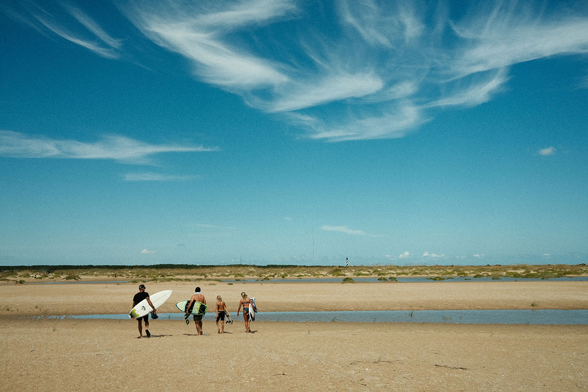 surfers walking across sand