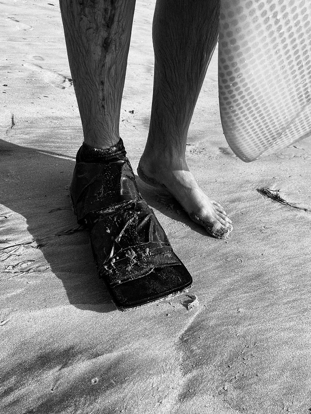 surfer on beach with broken toe boot