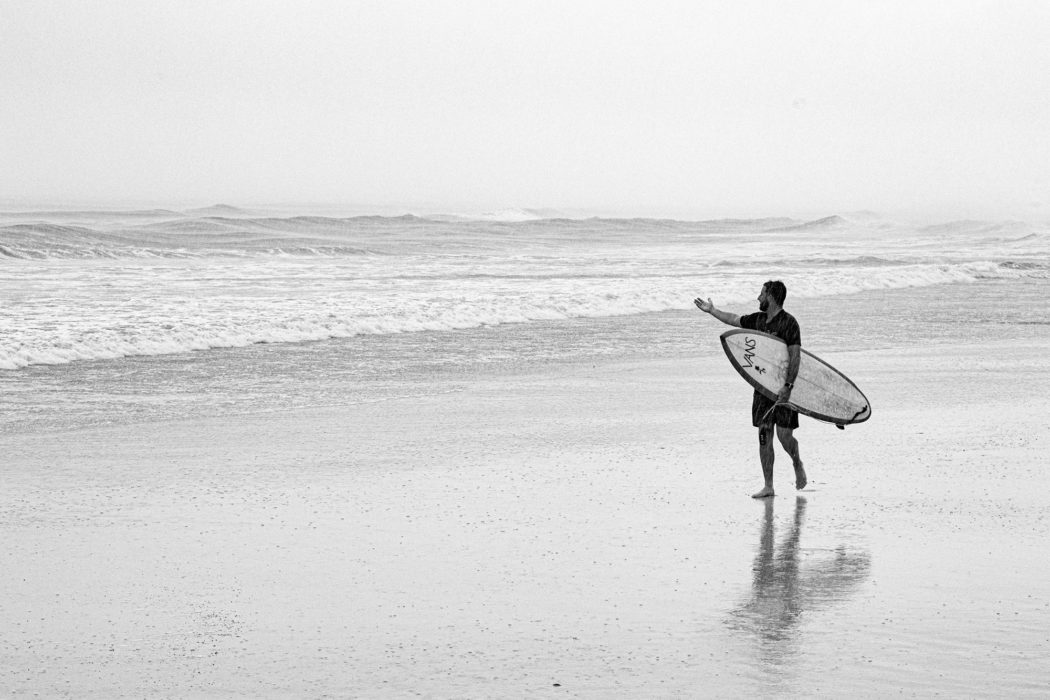 Surfer on beach in rain