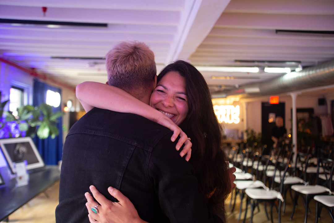 Photo of Marcus Russell Price hugging a woman at the event near the front of the room.
