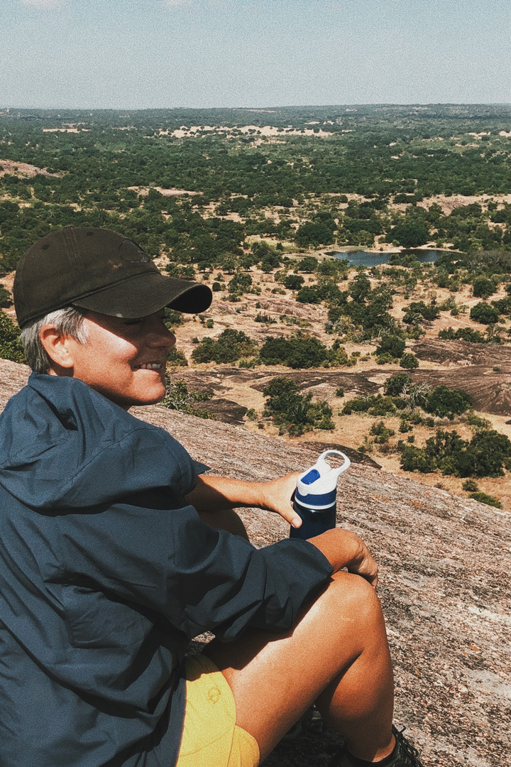 Photo of Donna Bruns, Global Product Director for Fjällräven, sitting on top of a mountain after a hike smiling for a picture.
