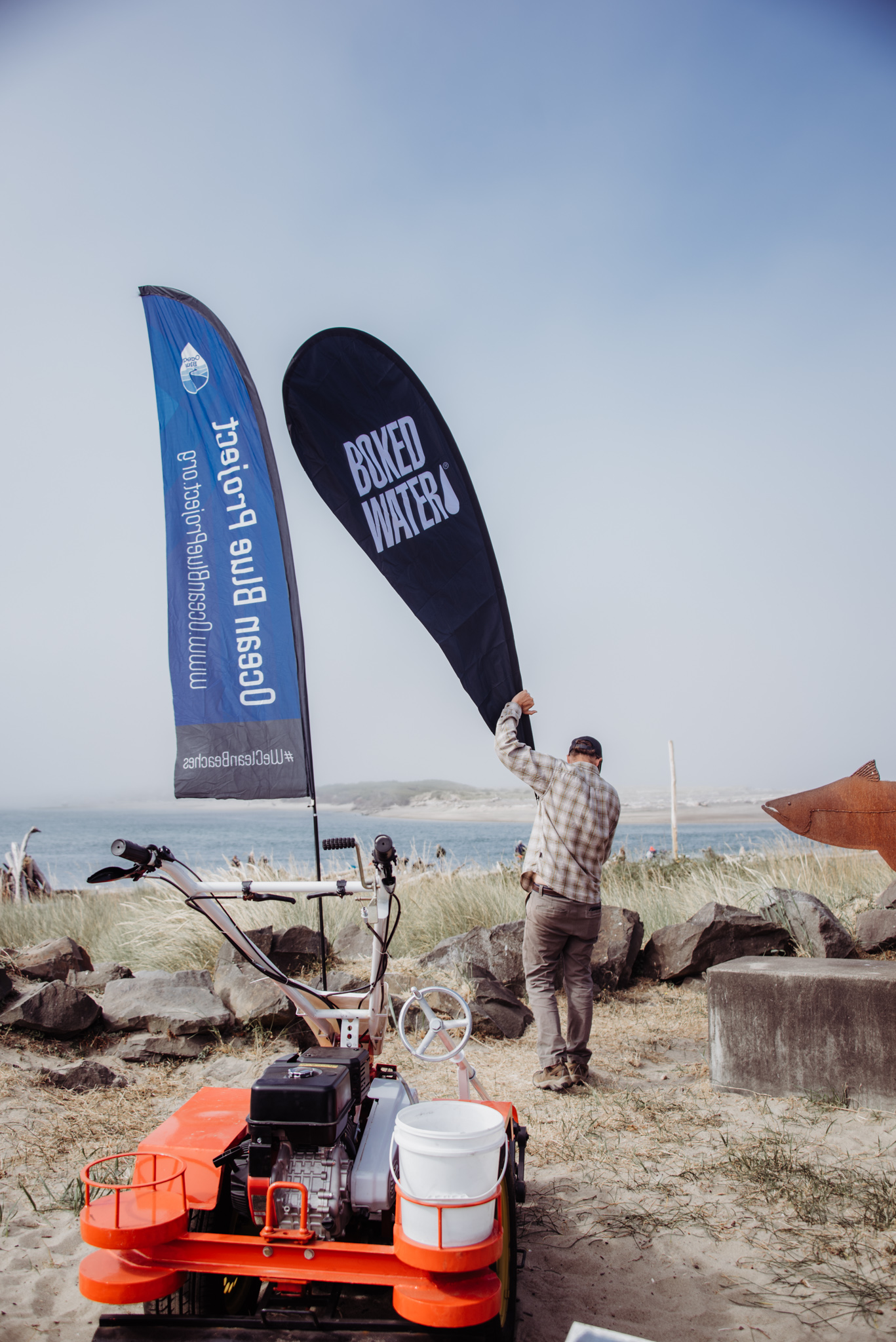 ocean blue and boxed water signs at an ocean blue project event. 
man putting up boxed water sign at the beach