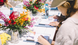 Photo of a table setting filled with colorful flower arrangements, magazines, notebooks, and Zen Water