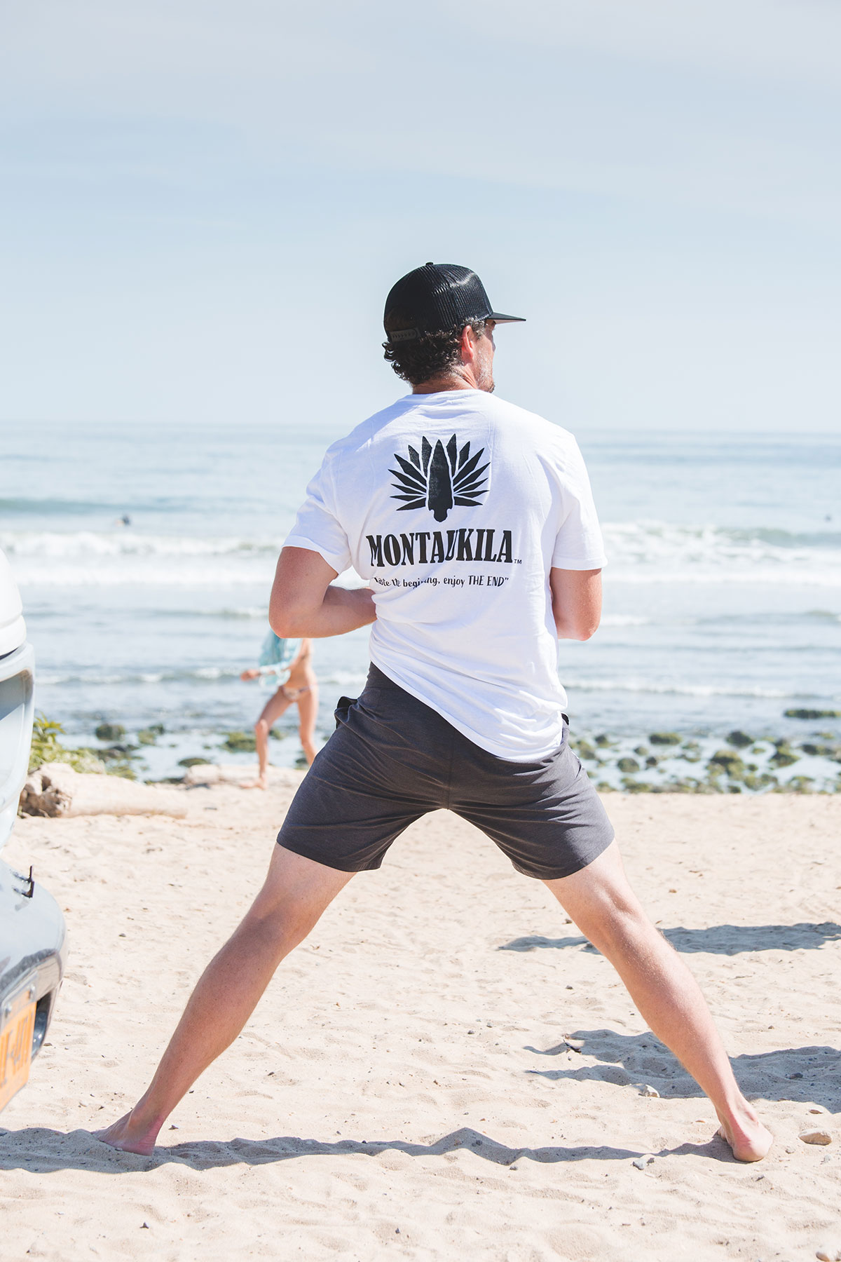 man in Montaukila t shirt standing on the beach 