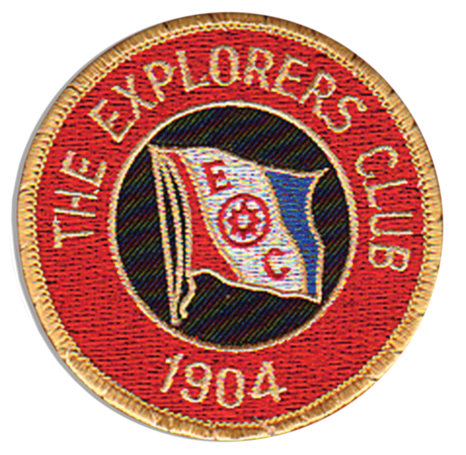 The Explorers Club patch from 1904. The patch is red with gold embroidered lettering and in the middle is the image of the Explorers Club flag.