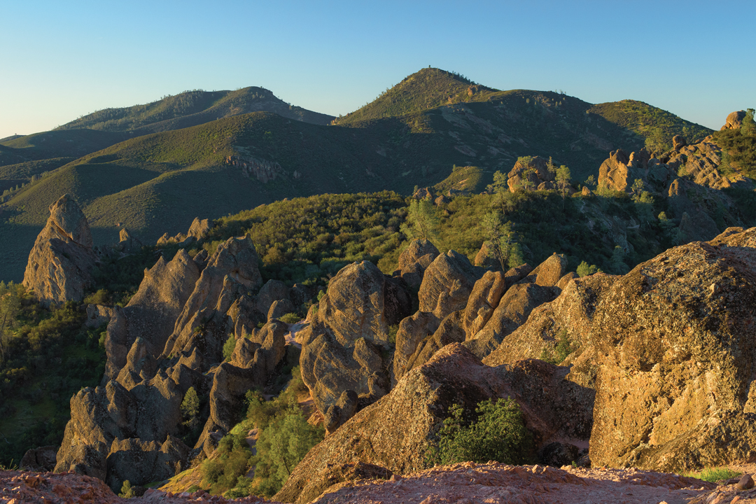 Landscape photo of Pinnacles National Park full of staggered, soft mountain peaks covered in trees and brush.