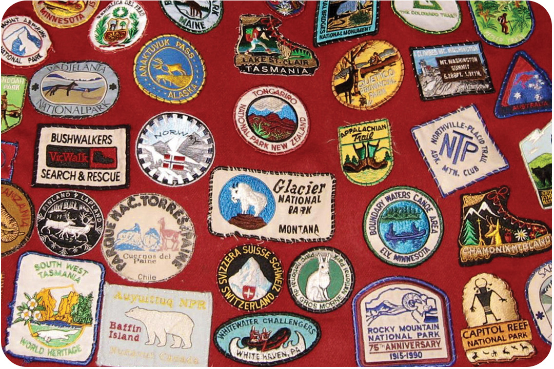 A large collection of all of J.R. Harris' travelers patches from the National Parks he has been to. All are attached to the back of a red coat. The patches vary in design and are for parks and monuments all over the world.