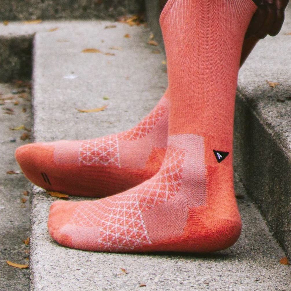 Close up photo of a red Arvin Goods Performance Hemp Biofiber Crew Sock on a person's feet. 