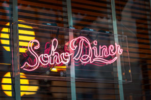 Pink neon sign reading "Soho Diner" on the outside of a window