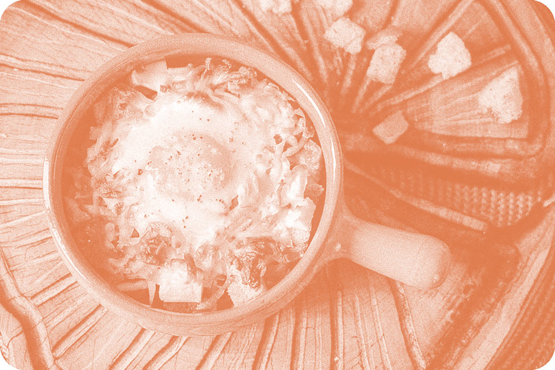 A ceramic bowl with a handle sticking off the side of it. Inside the bowl is a fried egg on top of pile of shredded food and squares of bread. The photo has been altered with a pink colored overlay.