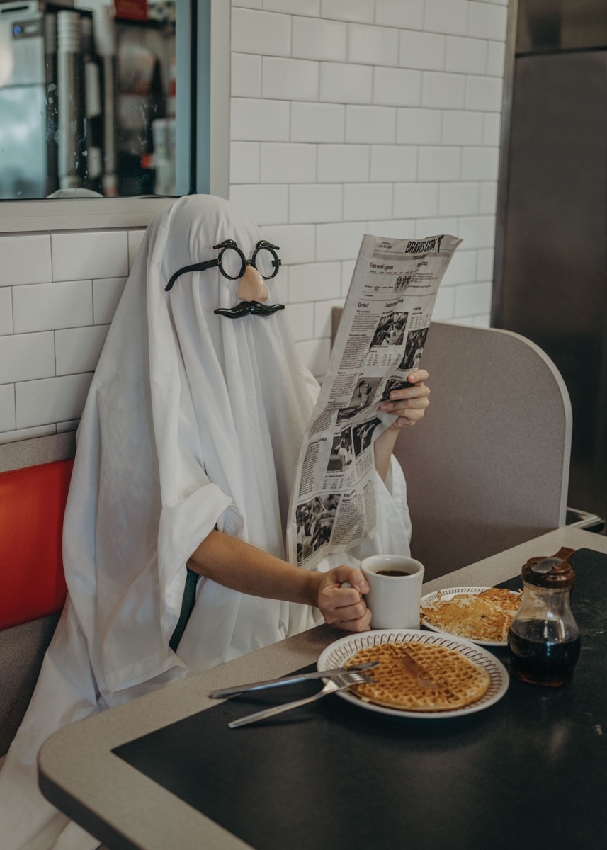 person dressed up as a ghost wearing fake glasses and mustache eating at Waffle House.