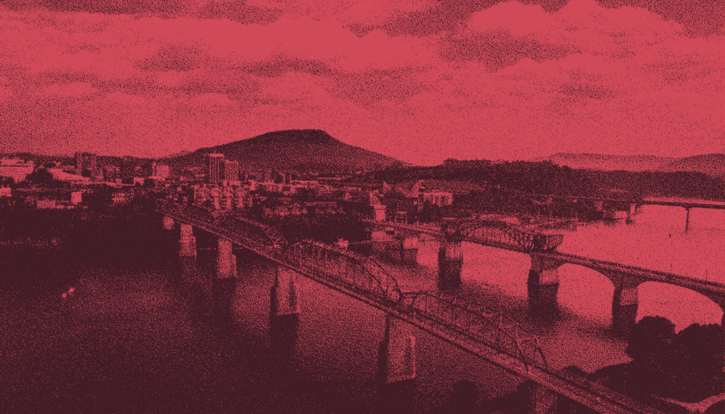Aerial photo of Chattanooga, Tennessee. There are three bridges coming from a small town over a body or water. The picture has been edited with a dark pink colored overlay.