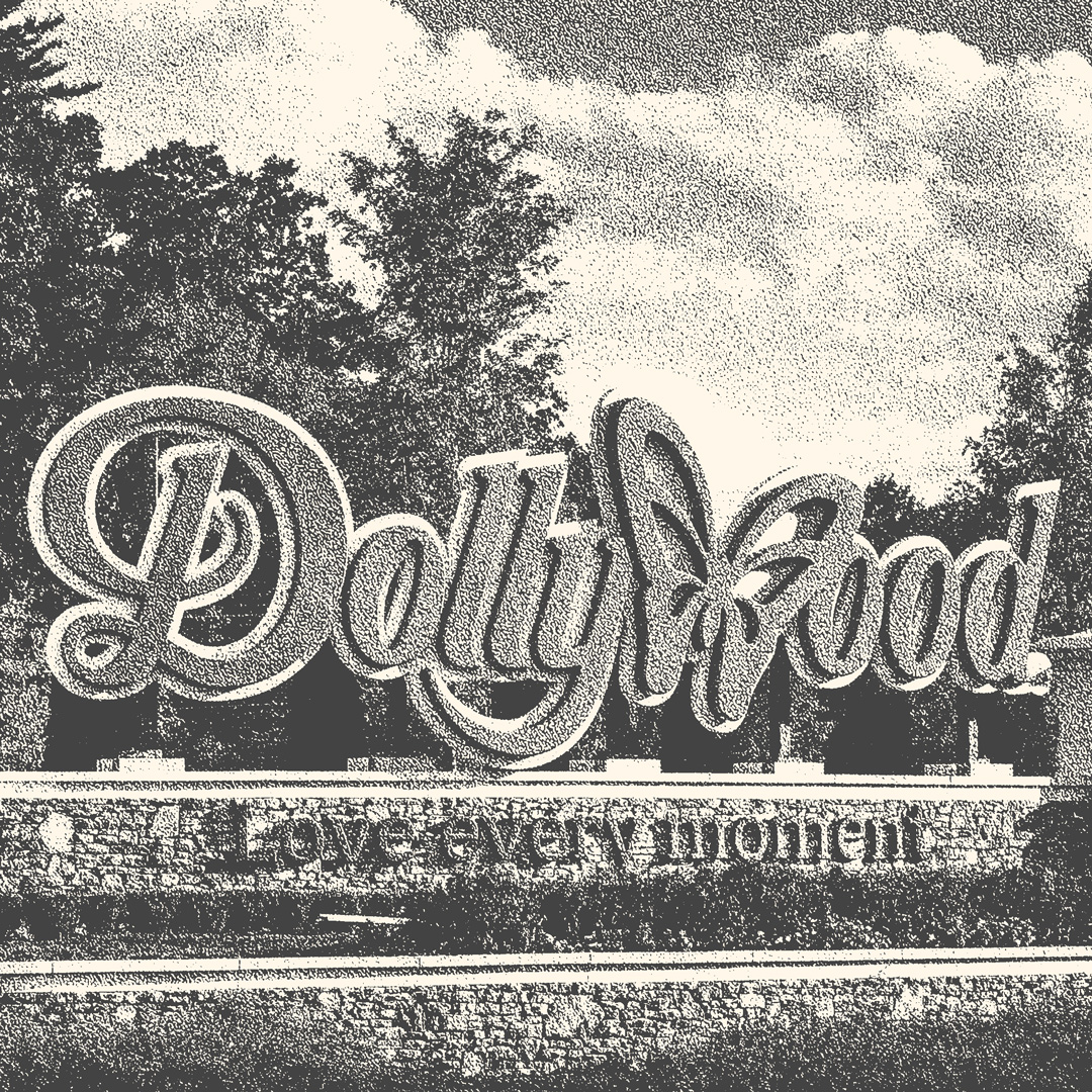 Dollywood theme park sign with the words "Dollywood" in a fancy serif font with the letter "W" being replaced by a butterfly. Underneath the words Dolly wood there is another sign that says "Love every moment". The photo is in black and white.