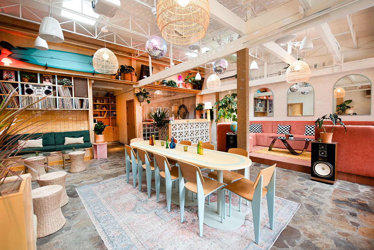 The JuneShine Williamsburg taproom, now open in New York City. It's a large room with warm tones and pastel colors. In the middle is a long communal table.
