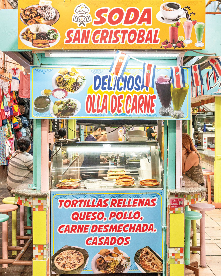 "Soda San Cristobal" food stall with bright advertisements covering it.