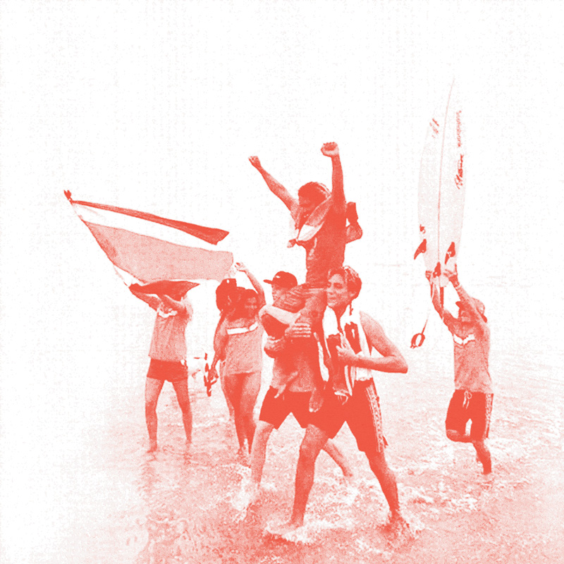 A group of people walking through the water on the shore of an ocean while holding up a man (Carlos Muñoz) on their shoulders. He has his fists raised in the air in celebration. On of the people walking is waving a large Costa Rican flag and another is holding a surf board vertically in the air. The entire image has a light, bright red colored overlay on it. 