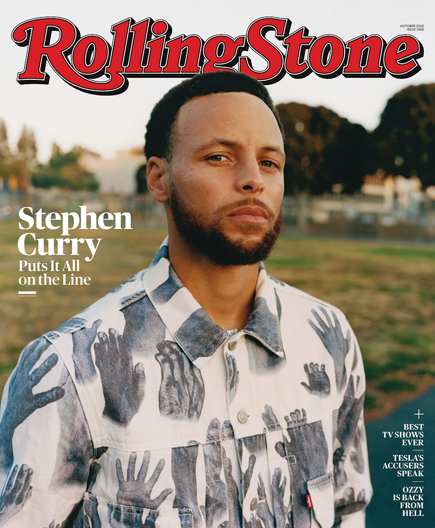 Rolling Stone magazine cover featuring basketball star Stephen "Steph" Curry standing in a blurred out grassy field. Steph's body is angled slightly to the side and he is looking at the camera. He is wearing a white collared shirt decorated with illustrations of life-like grey hands.
