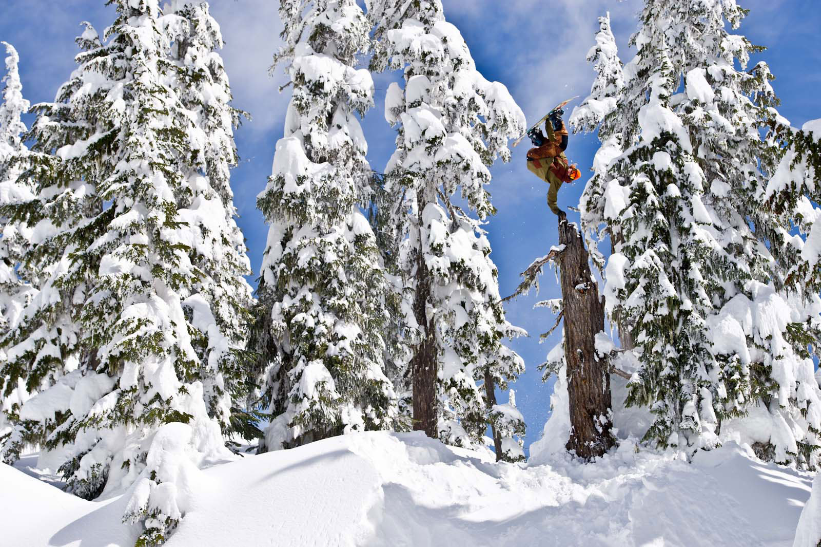 Person jumping on a snowboard in the backcountry of a mountain