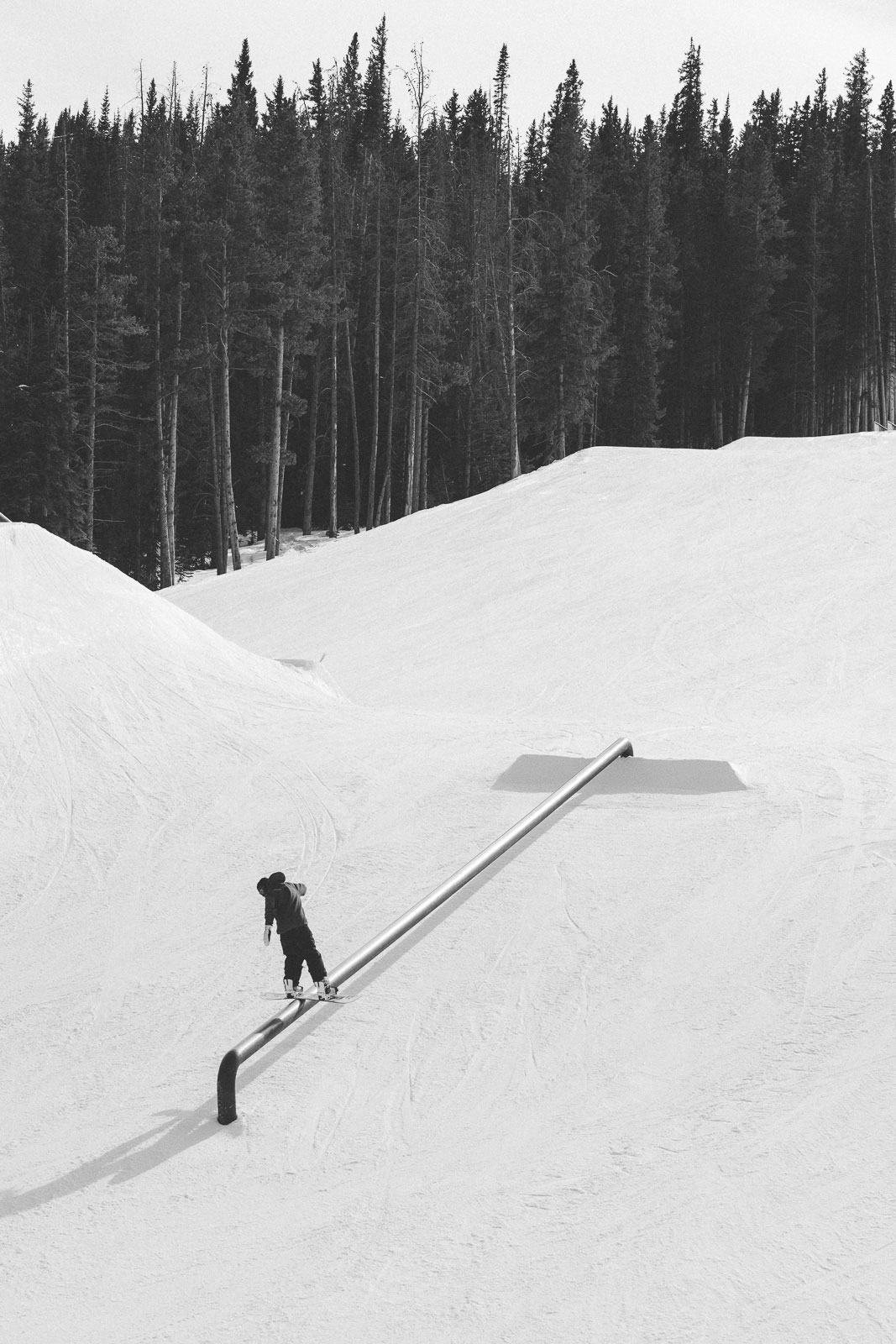 Snowboarder going down rail in terrain park