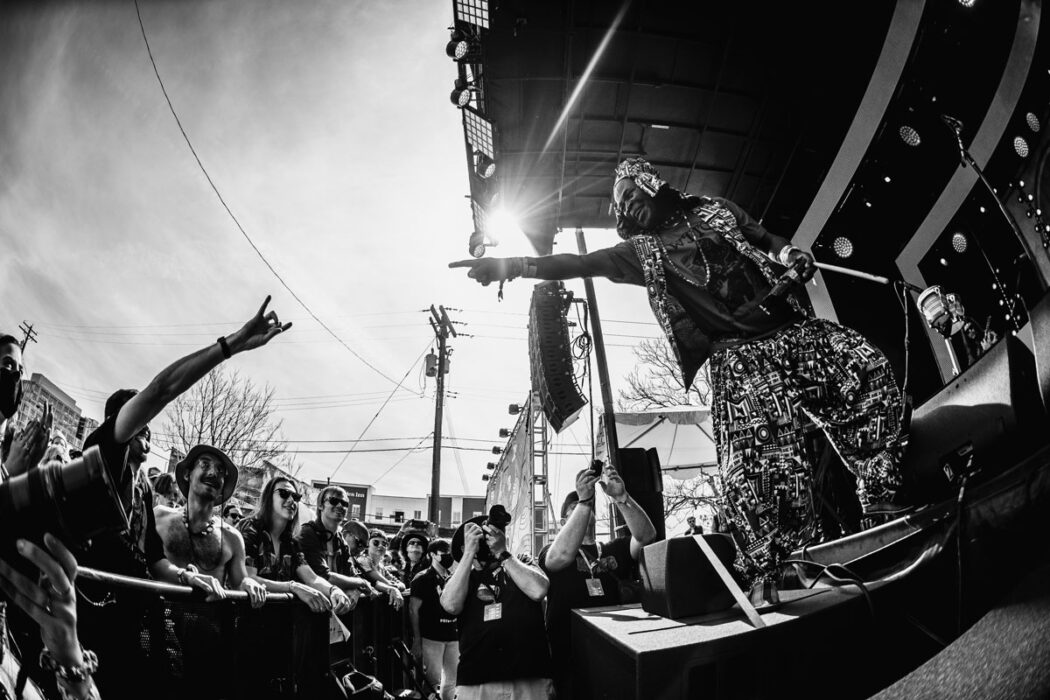 WITCH performing on an outdoor stage with man reaching out to Jagari in black and white
