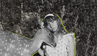 Black and white photo of a woman wearing a frilly dress and a mtaching colored headband. She is sitting on the ground outside while a deer stands next to her and is resting its head underneath the woman's head. The woman and the deer have a green-colored outline around the two of them.