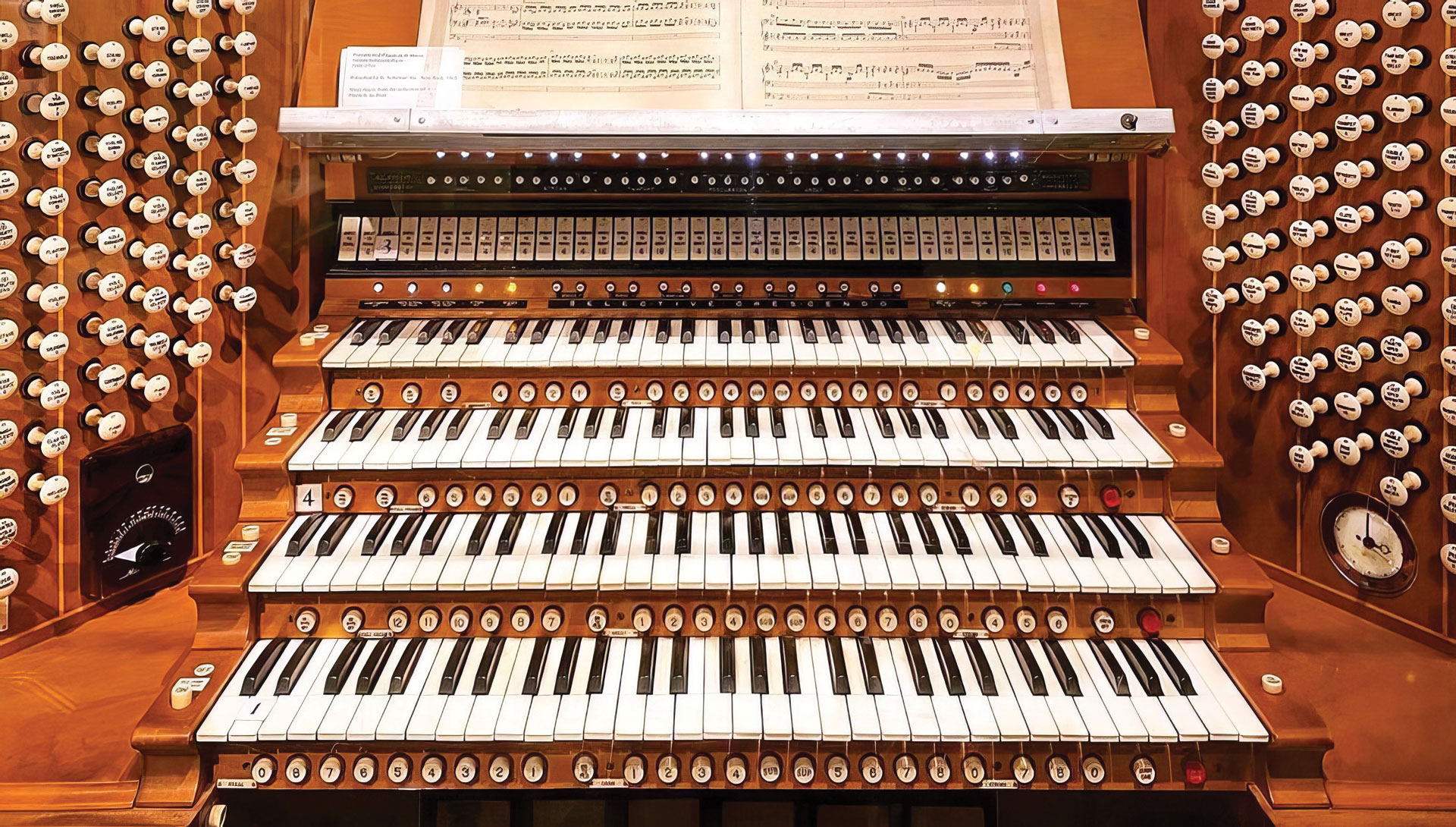 Close-up image of an organ with sheet music and all of the repeating keys and buttons.