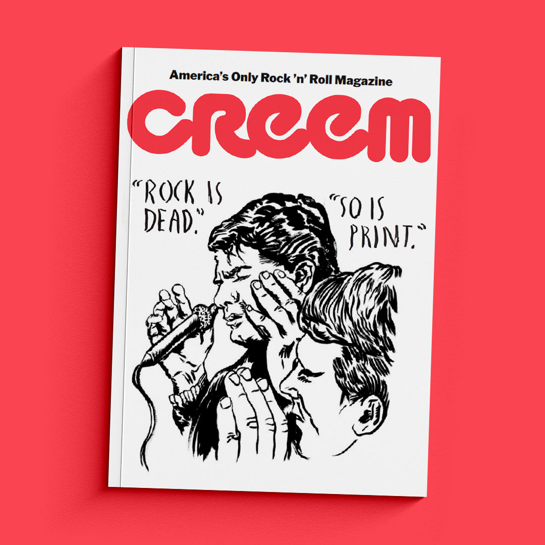 Photo of CREEM's first issue since its relaunch. The magazine is siting against a red/pink background and is all white with a black illustrated drawing of two men close up singing into microphones. The words "ROCK IS DEAD." and "SO IS PRINT" appear to be handwritten underneath the red/pink title of the magazine.