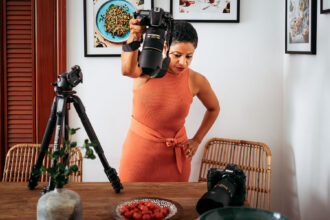 A woman holding a camera over a plate of food