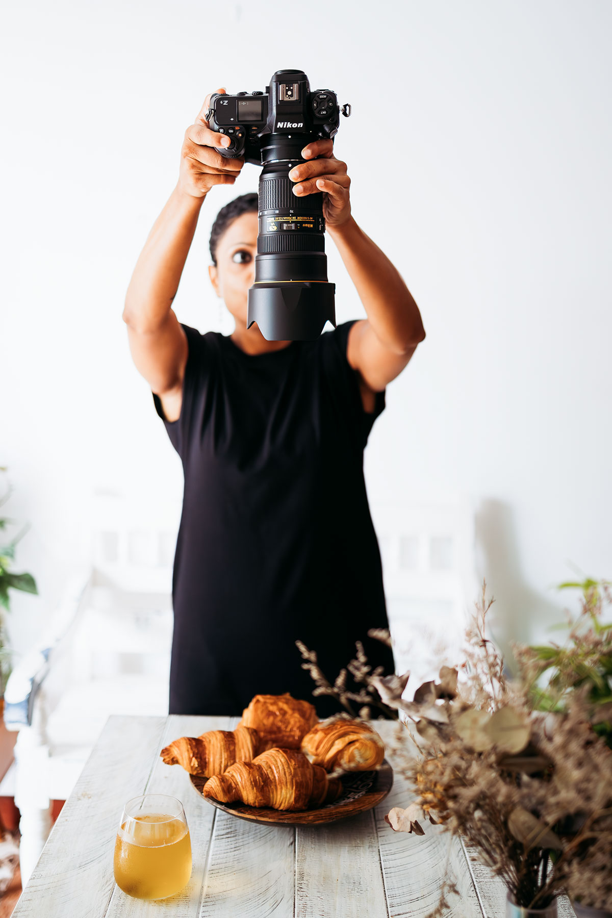 A woman holding a camera to take a picture of a bowl of pastries