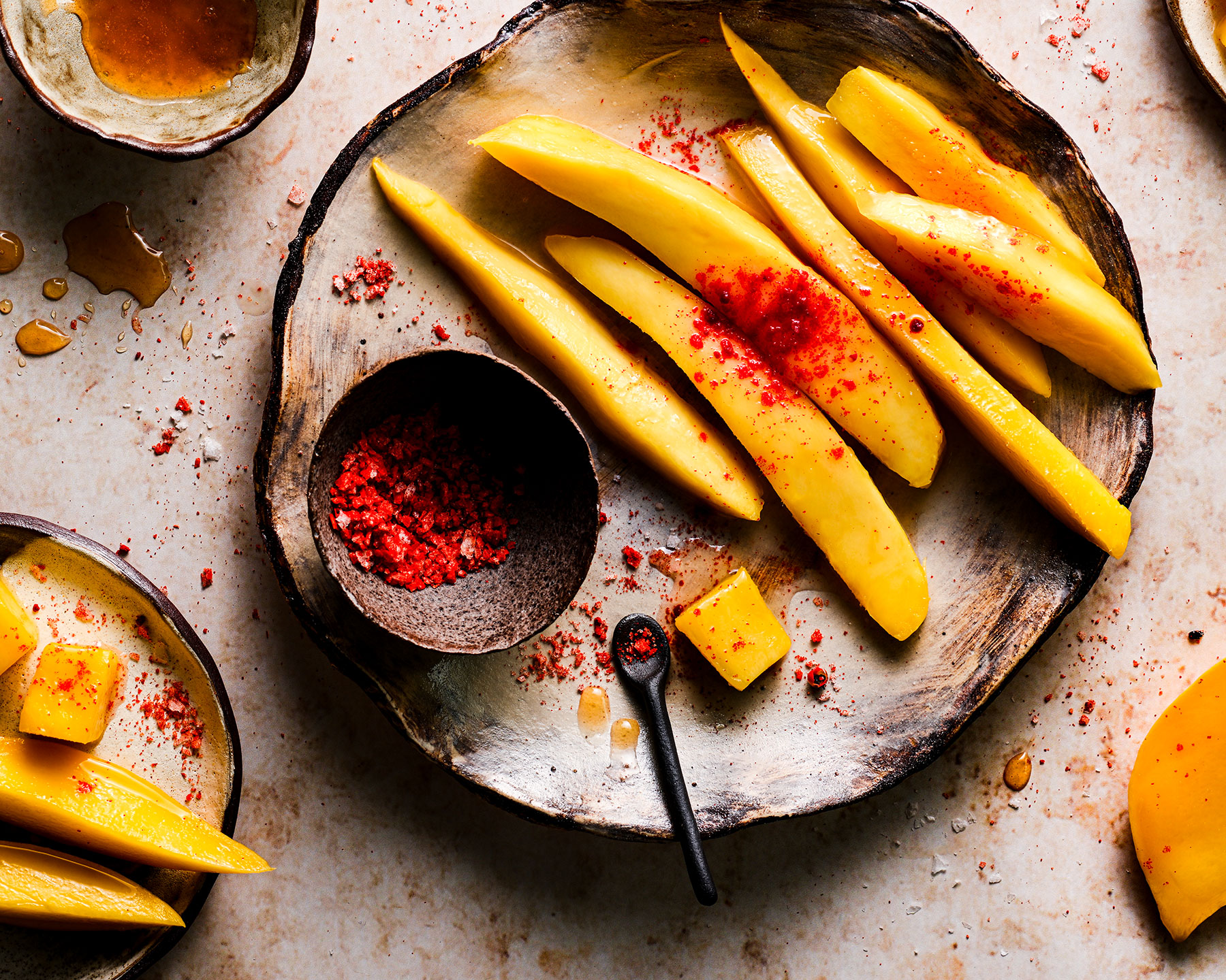A picture of sliced mango with chili sprinkled on top