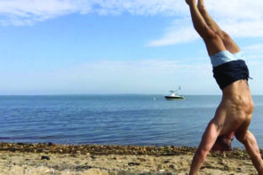 Adam Rosante does a handstand on a beach