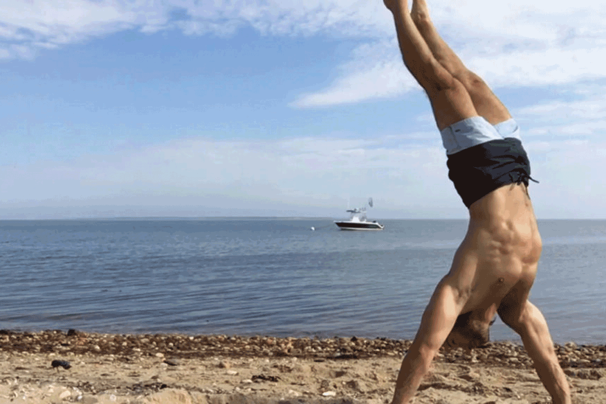 Adam Rosante doing a handstand on the beach