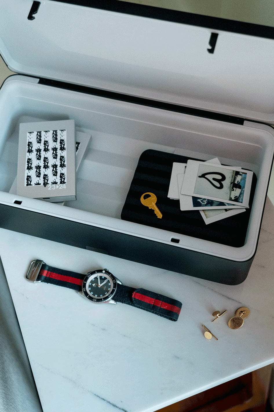 TROVA safe with key, polaroids, cuff links, and a watch.  