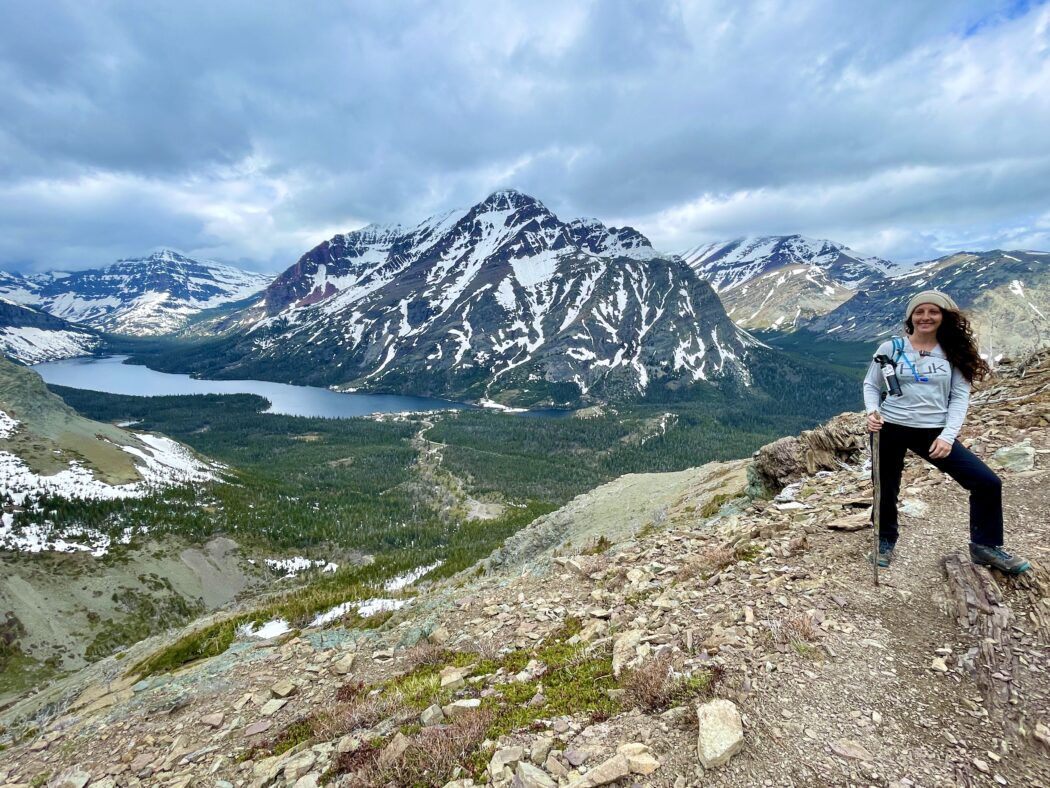 woman hiking with mountain and lake in the dsitance at glacier national park