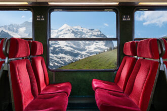 view of mountains through window with red seats in front