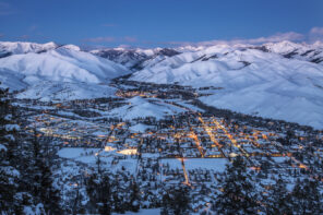 Nightime aerial shot of Sun Valley, Idaho. Snow covered mountains surround the golden lit streets from lamposts and cars.